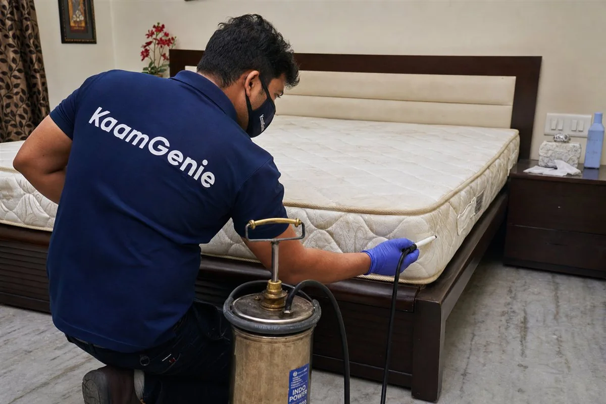 KaamGenie technician treating a mattress seam and bed frame joints for bed bugs in a Delhi bedroom