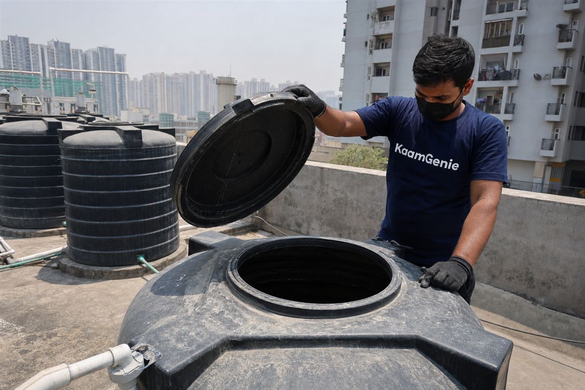 Heavy white calcium scale and rust-coloured sediment crusting the inside wall of a Noida rooftop water tank after a hot summer