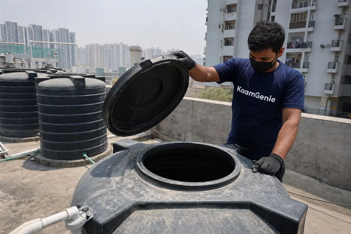 Heavy white calcium scale and rust-coloured sediment crusting the inside wall of a Noida rooftop water tank after a hot summer