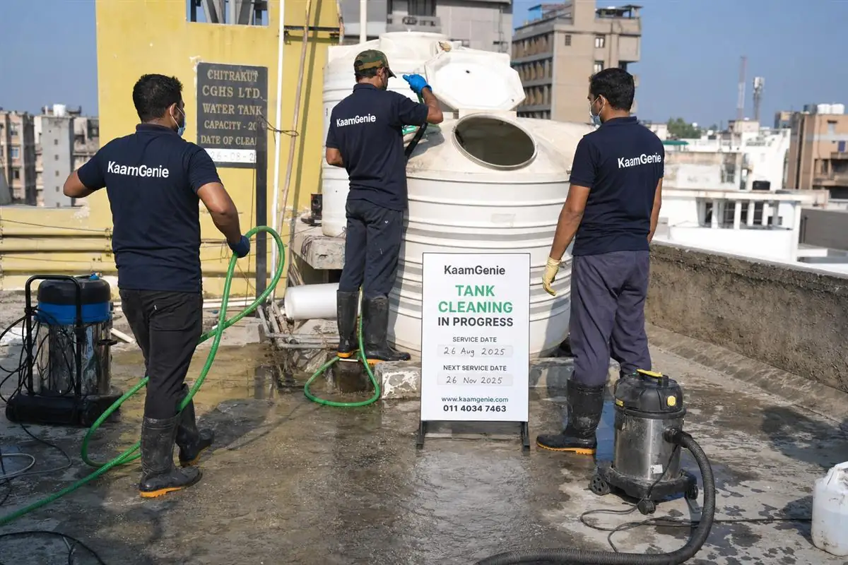 KaamGenie team in navy uniforms servicing rooftop overhead tanks of a CGHS group housing society in Delhi