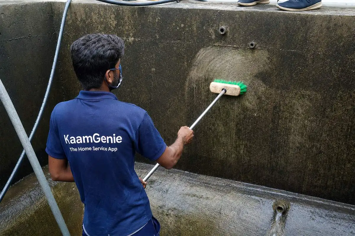 KaamGenie crew scrubbing the rough interior walls of a large RCC concrete water tank in an older Delhi kothi