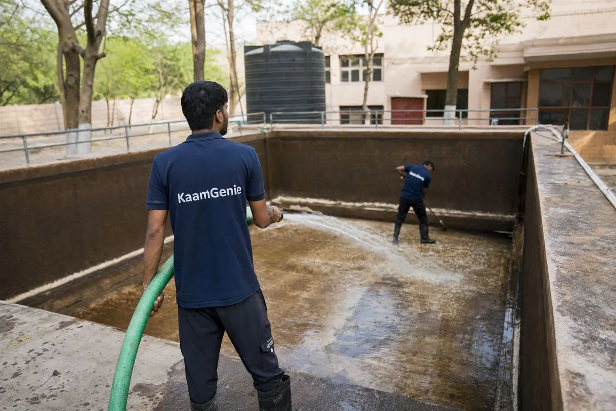 KaamGenie crew in navy shirts cleaning a very large underground water reservoir at a Gurgaon hospital or school campus