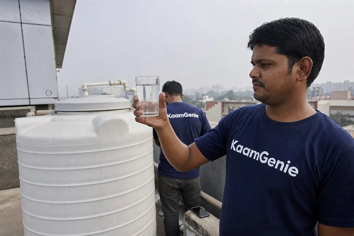 KaamGenie crew member testing water clarity in a glass beside a freshly cleaned institutional water tank in Noida