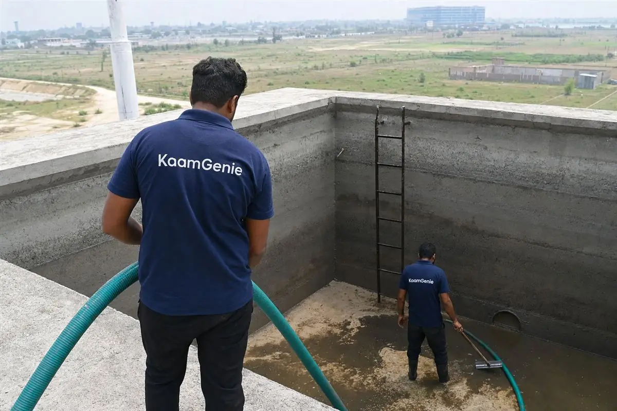 KaamGenie crew cleaning the underground reservoir of a new society in the Jewar YEIDA airport corridor with open land behind