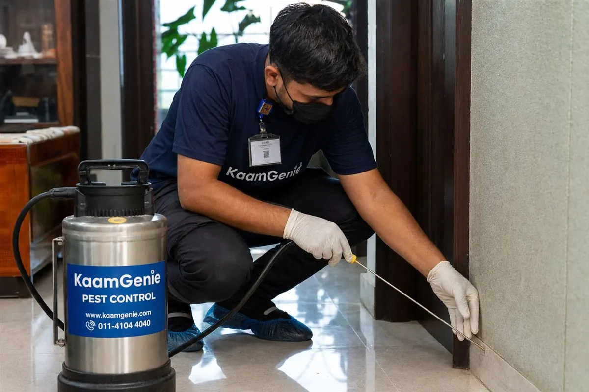 KaamGenie pest control technician injecting anti-termite chemical into a ground-floor flat in Abul Fazal Enclave, Okhla, South-East Delhi