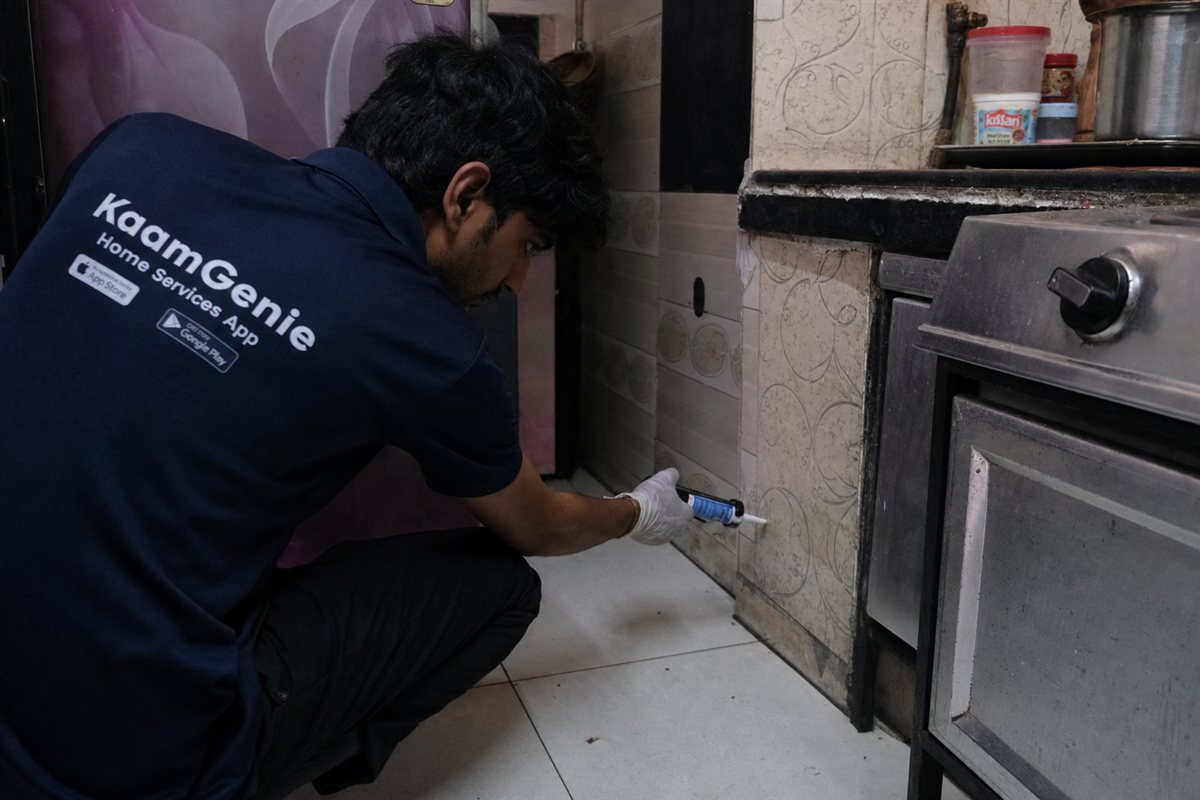KaamGenie pest control technician applying cockroach gel bait in a flat in Ambedkar Nagar, South Delhi