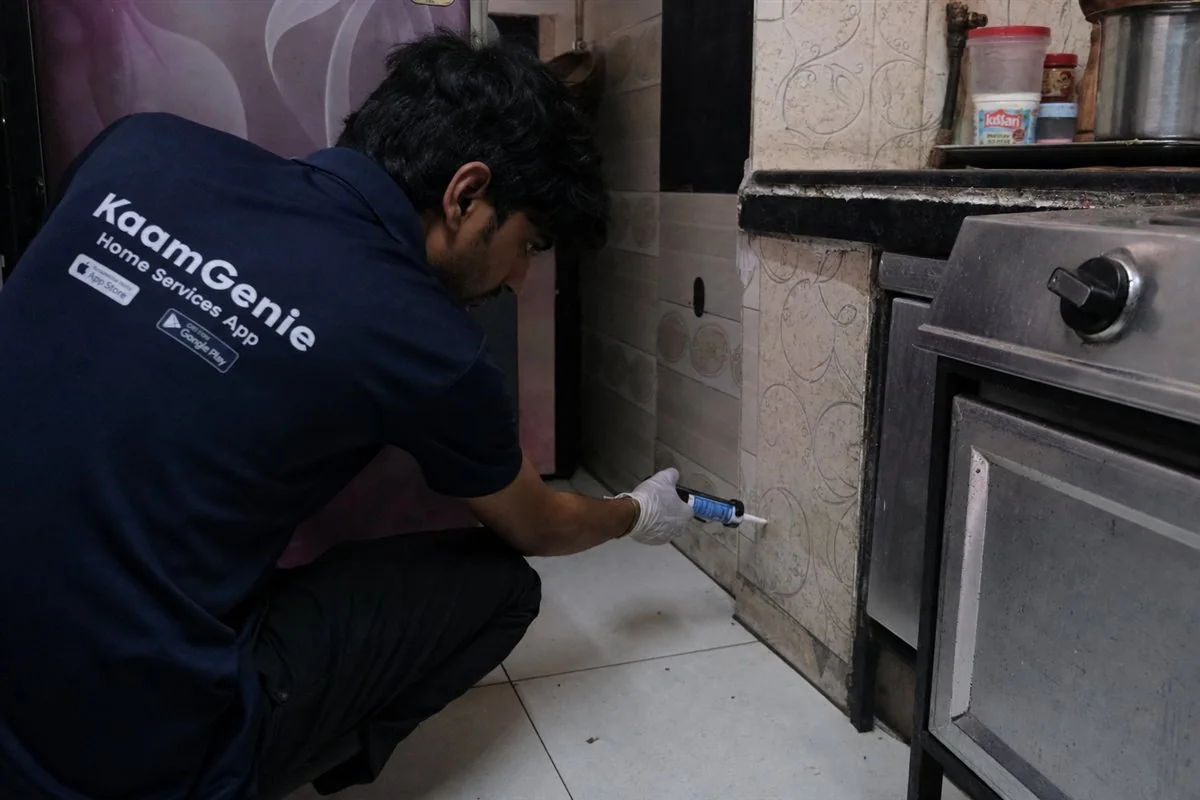 KaamGenie pest control technician applying cockroach gel bait in a flat in Ambedkar Nagar, South Delhi