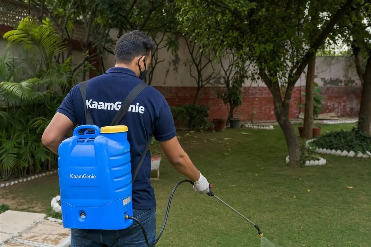 KaamGenie pest control technician treating a Chattarpur farmhouse garden in South Delhi