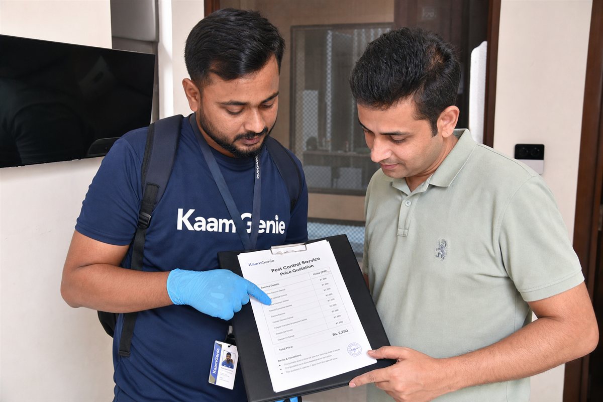 KaamGenie pest-control technician going through a treatment price list with a homeowner at a Delhi flat