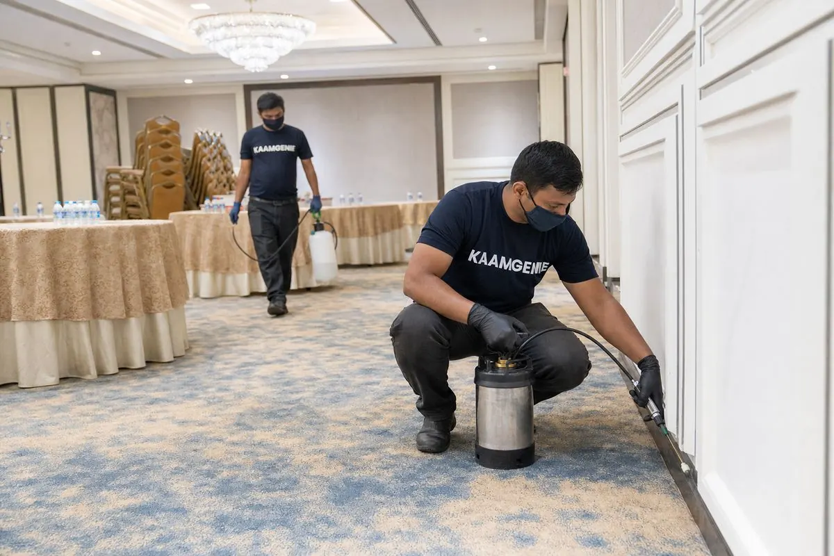 KaamGenie commercial pest control technician inspecting a Delhi hotel kitchen before service hours, with documentation clipboard