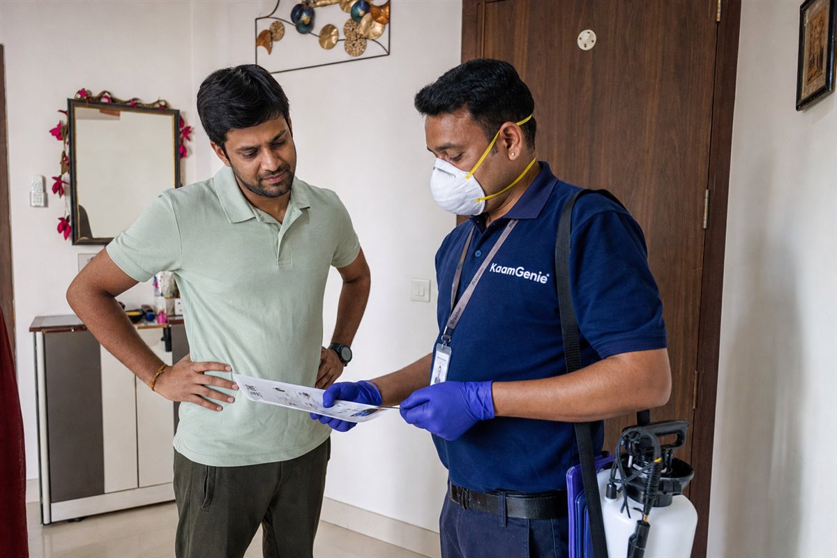 KaamGenie technician carrying out general pest control in a rented Delhi flat while the tenant looks on