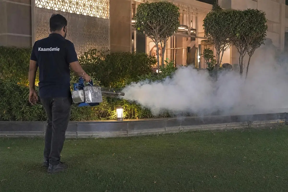 KaamGenie pest control technician fogging a banquet-hall lawn for mosquitoes in Ghitorni on MG Road, South Delhi