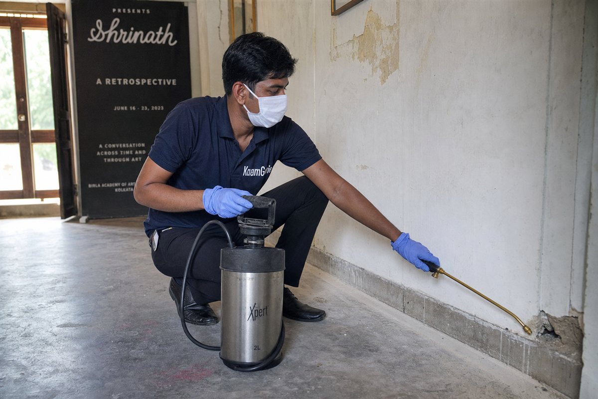 KaamGenie pest control technician treating an old village house and art gallery building for termites and rodents in Lado Sarai near Qutub, South Delhi
