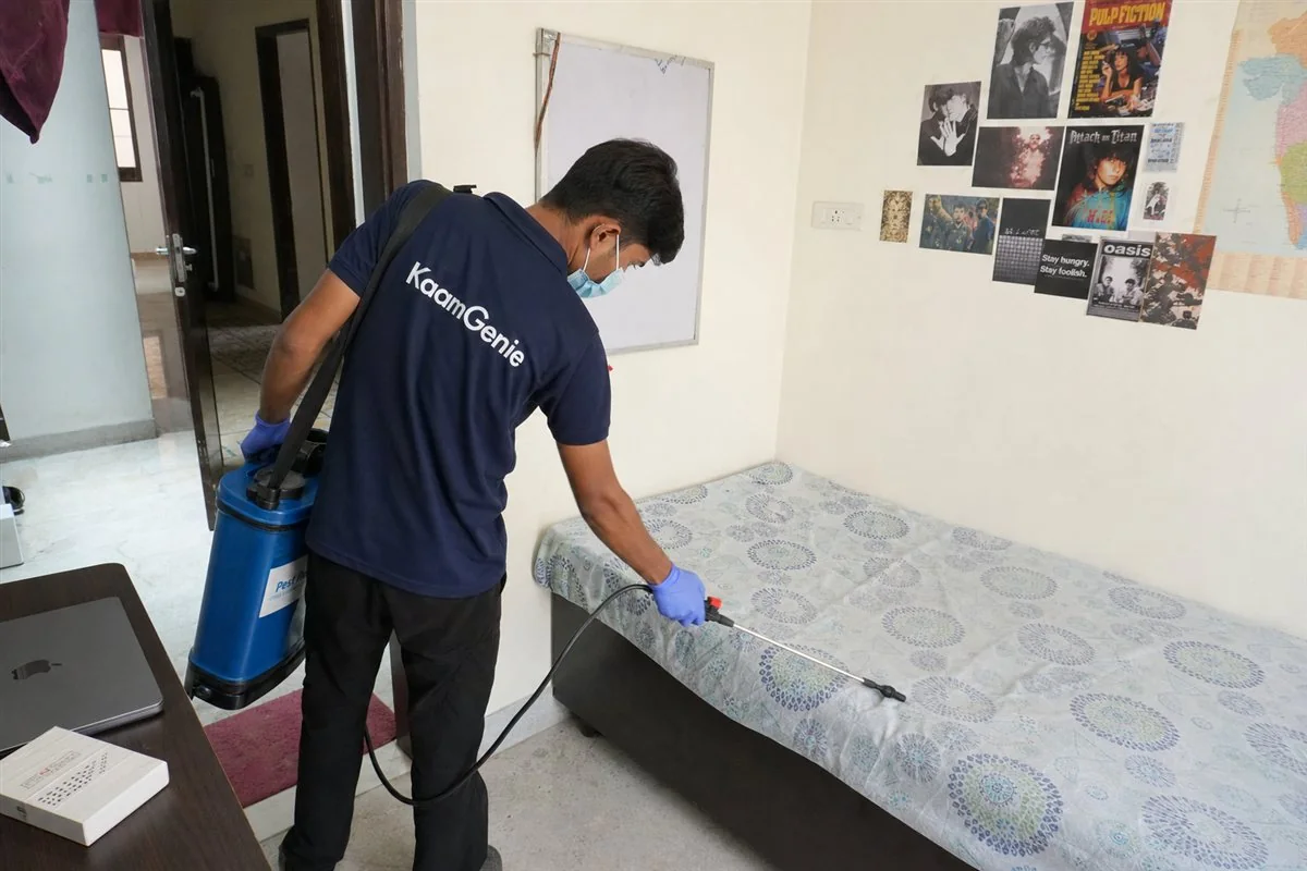 KaamGenie pest control technician treating a PG room for bed bugs in Munirka near JNU, South Delhi