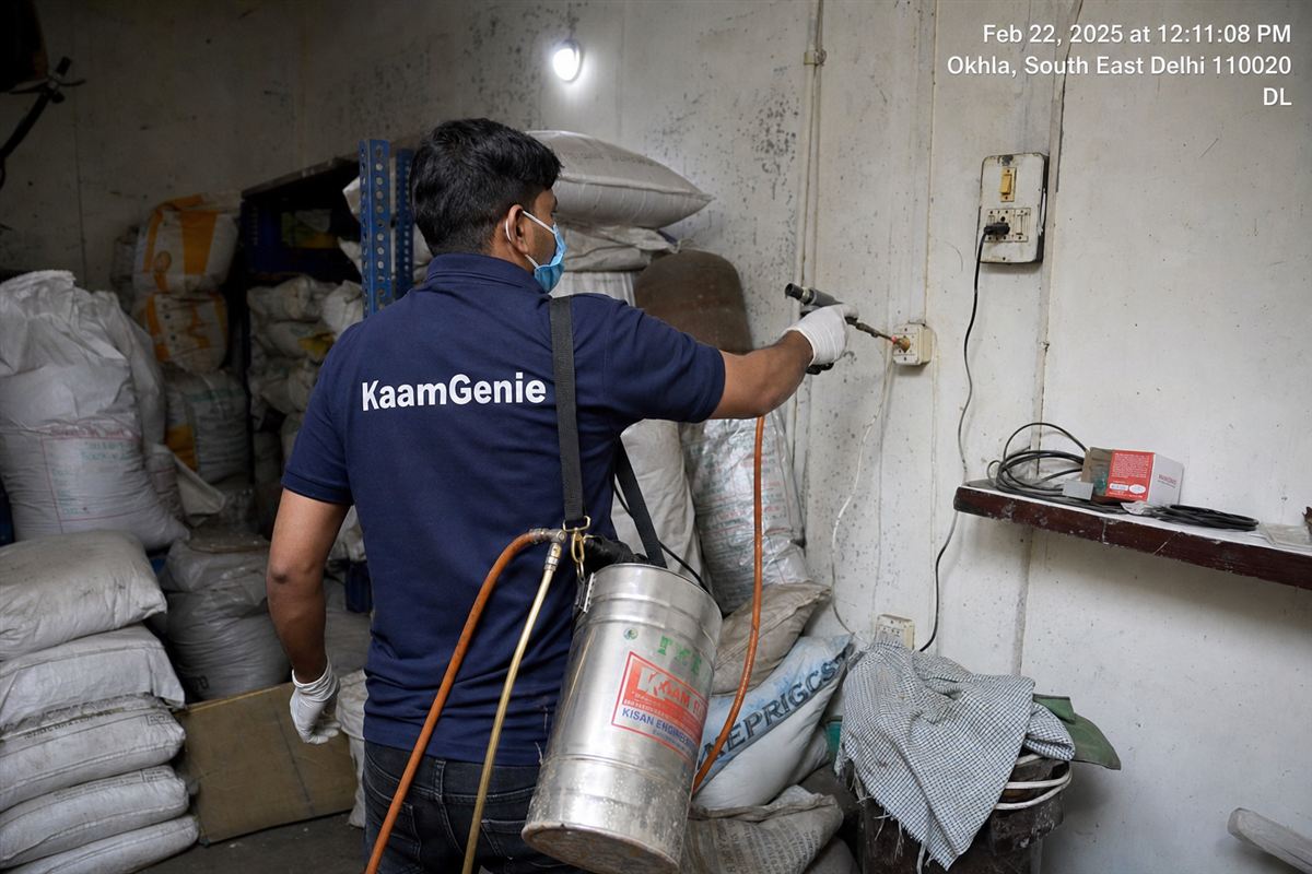 KaamGenie pest control technician treating a mixed industrial and residential building in Okhla Phase 3, South-East Delhi