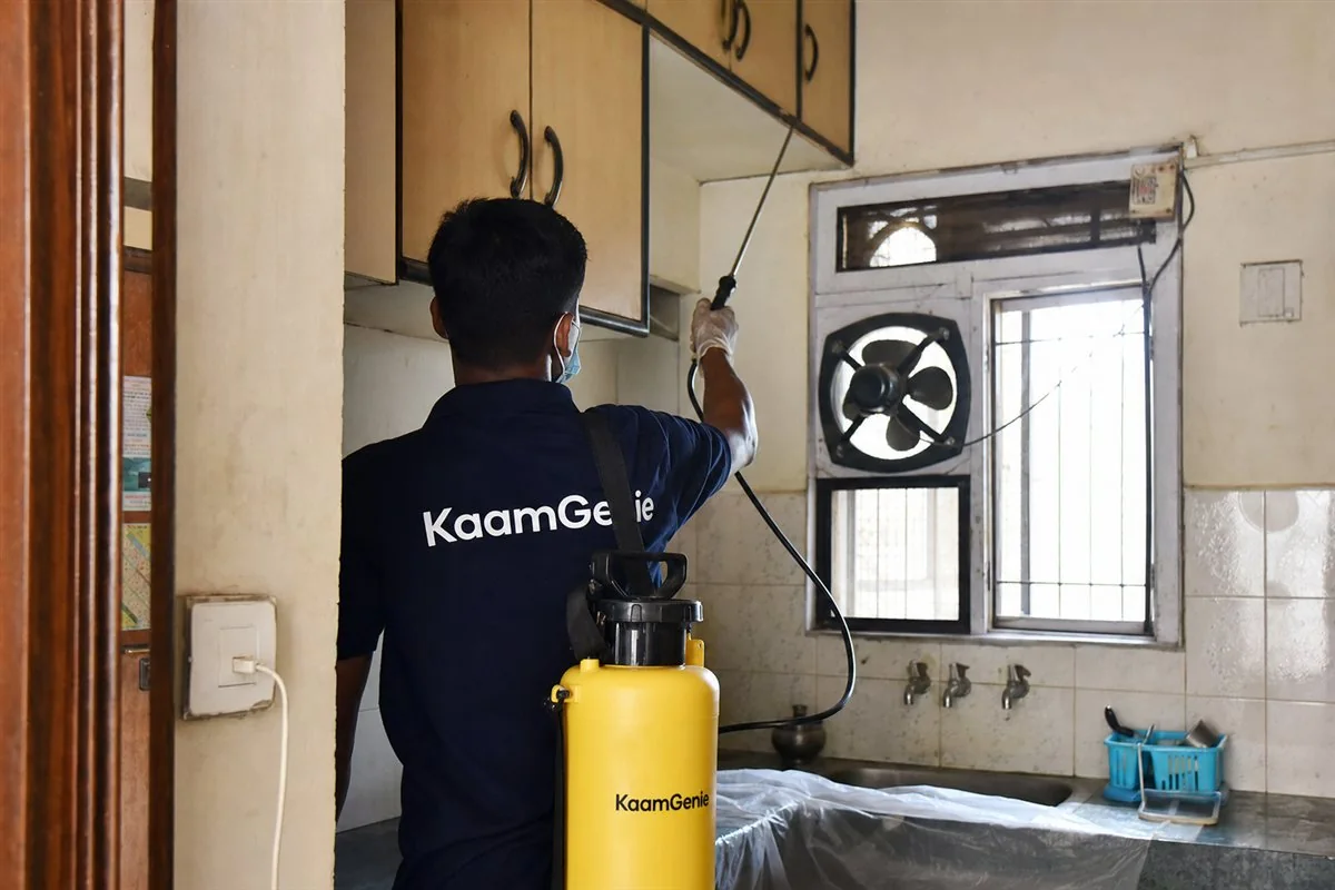 KaamGenie pest control technician treating a DDA flat kitchen in Srinivaspuri, South Delhi