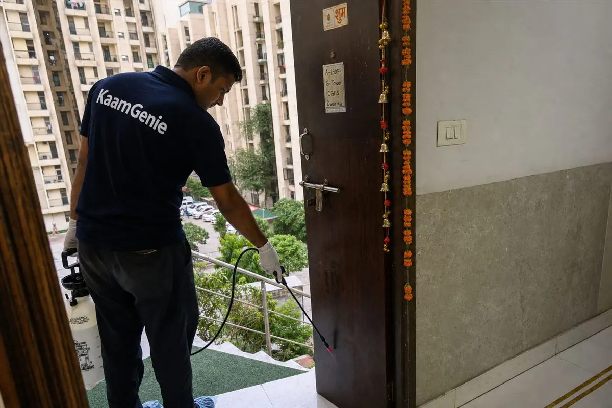 KaamGenie pest control technician servicing a Dwarka society flat in West Delhi with pet-safe equipment
