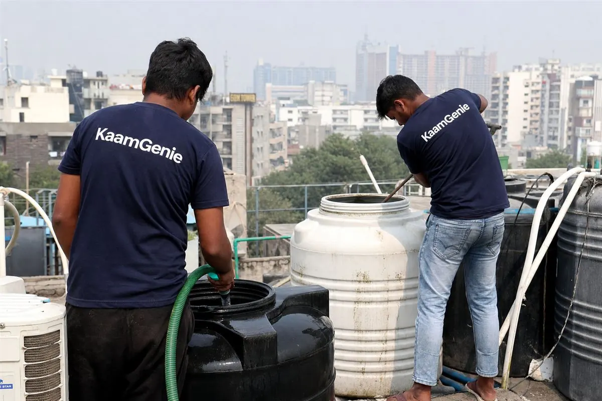 KaamGenie crew cleaning the rooftop water tanks of a dense PG and co-living building near a Noida college and office belt