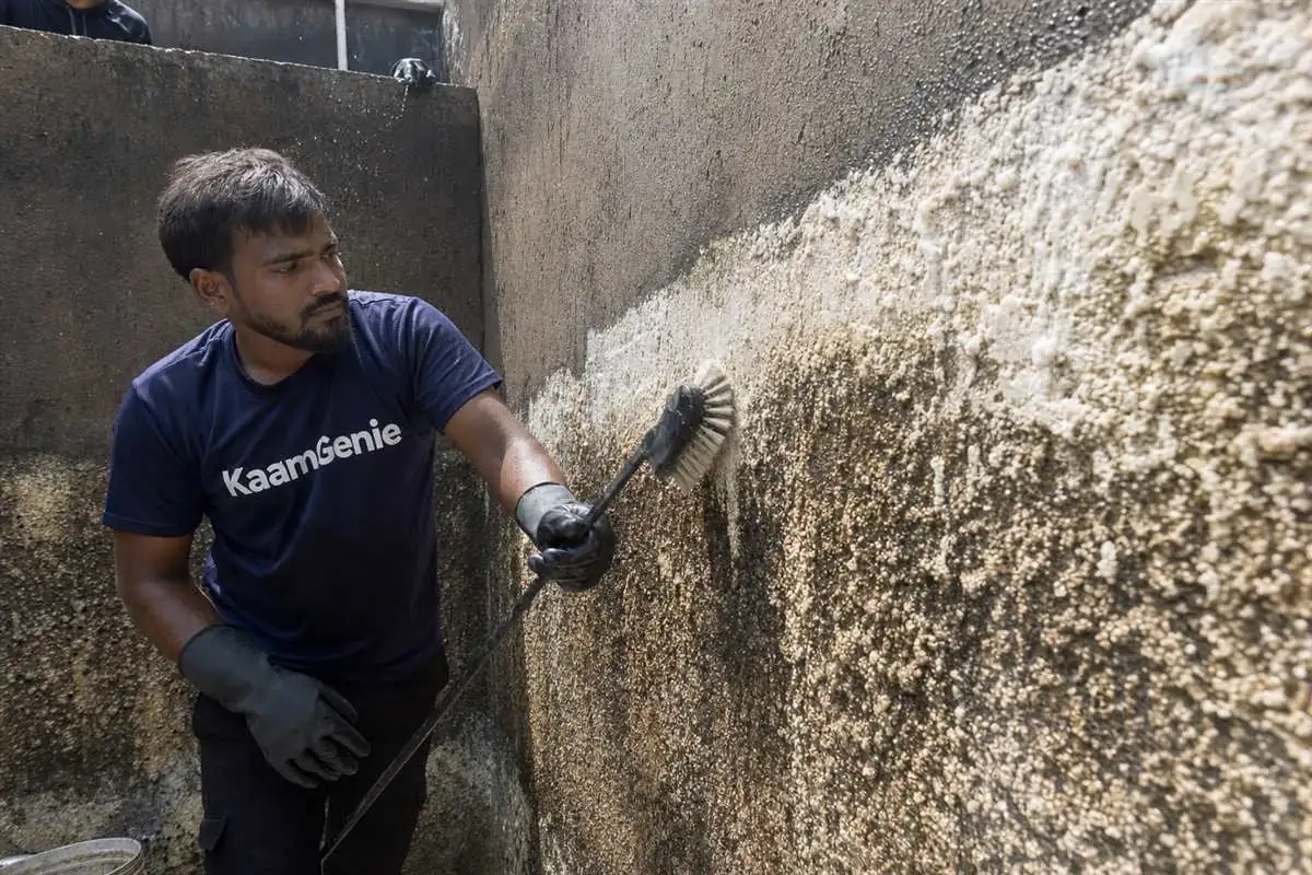 Thick white-grey calcium scale crust built up inside a concrete RCC reservoir wall in Noida from hard borewell water