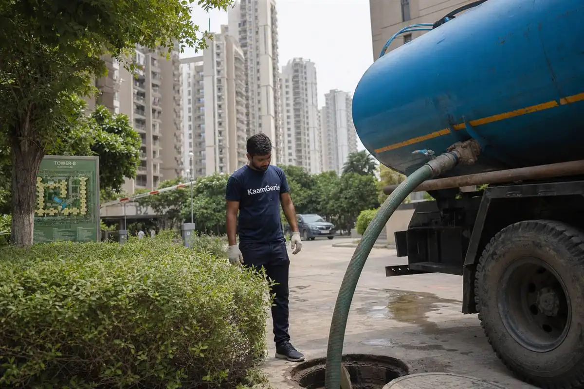 A private water tanker discharging into an underground reservoir at a Gurgaon condominium while a KaamGenie crew member inspects the inlet