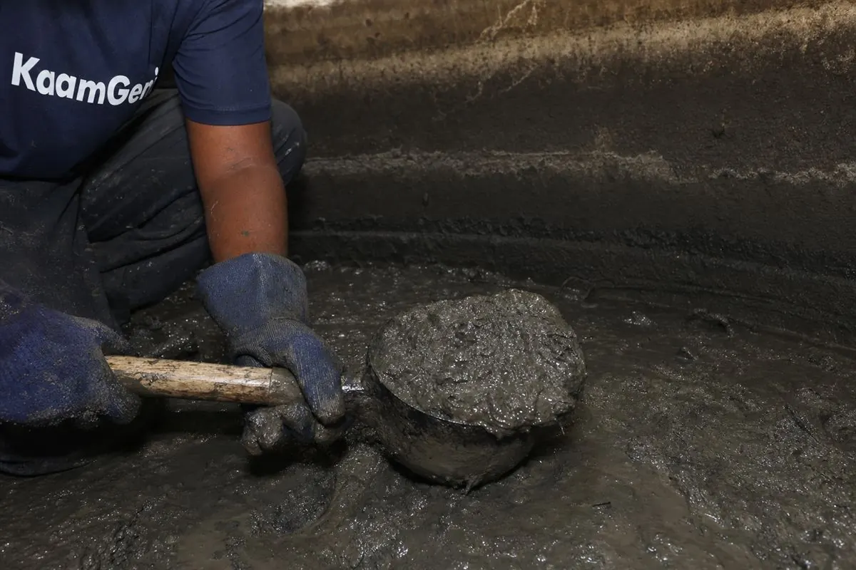 KaamGenie technician entering a Gurgaon underground sump through a manhole with a colleague acting as spotter, ventilation running and lighting in place
