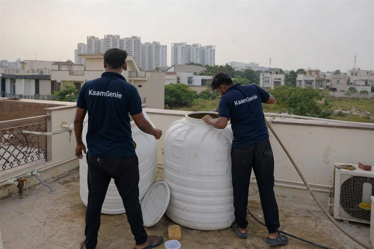 KaamGenie crew in navy shirts cleaning a rooftop water tank on a luxury independent villa in a Noida sector