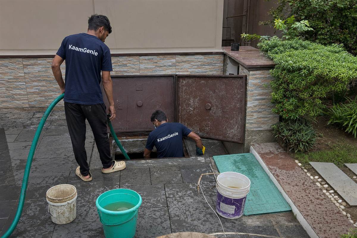 KaamGenie worker in a navy shirt cleaning a private underground sump at a Noida villa