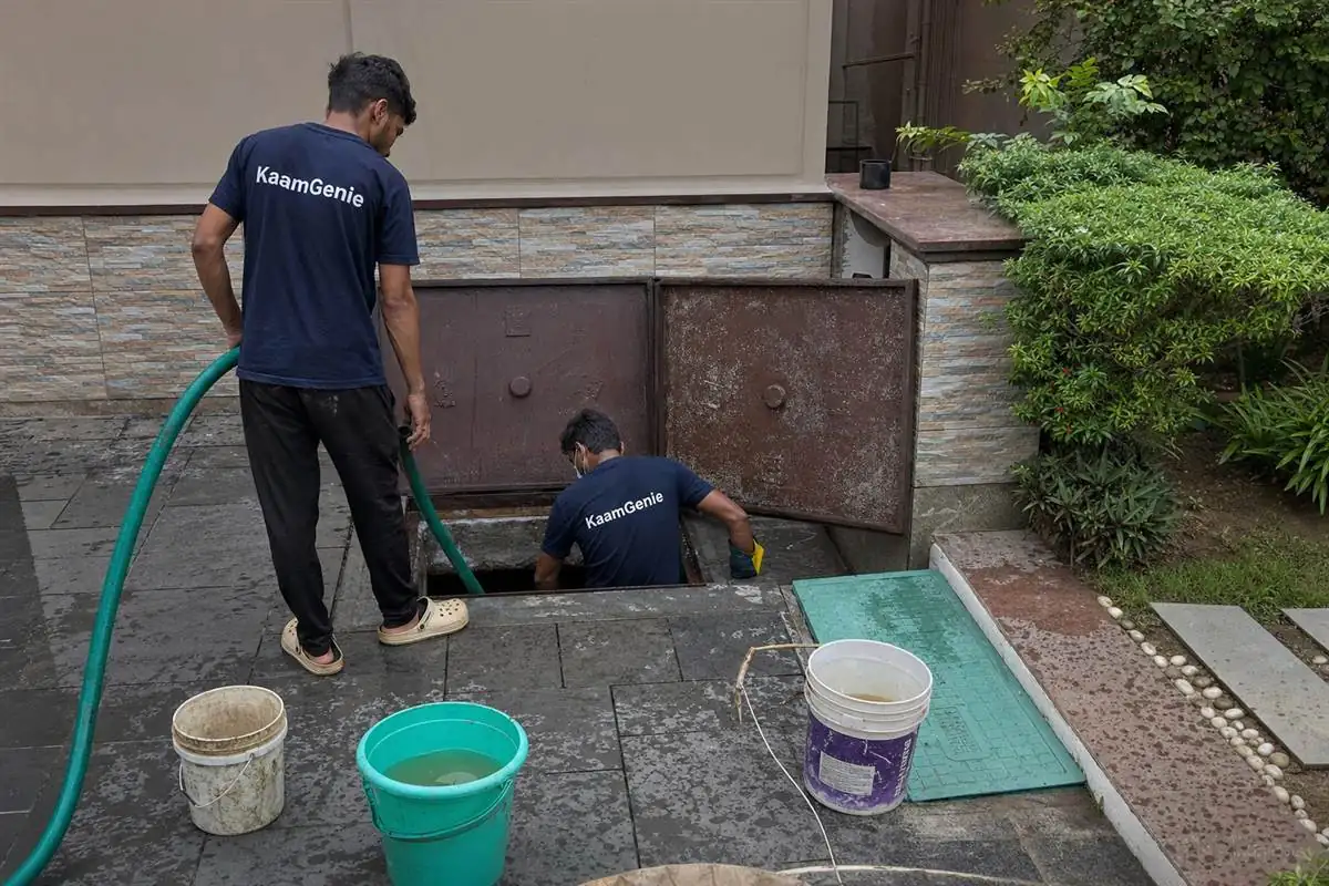 KaamGenie worker in a navy shirt cleaning a private underground sump at a Noida villa