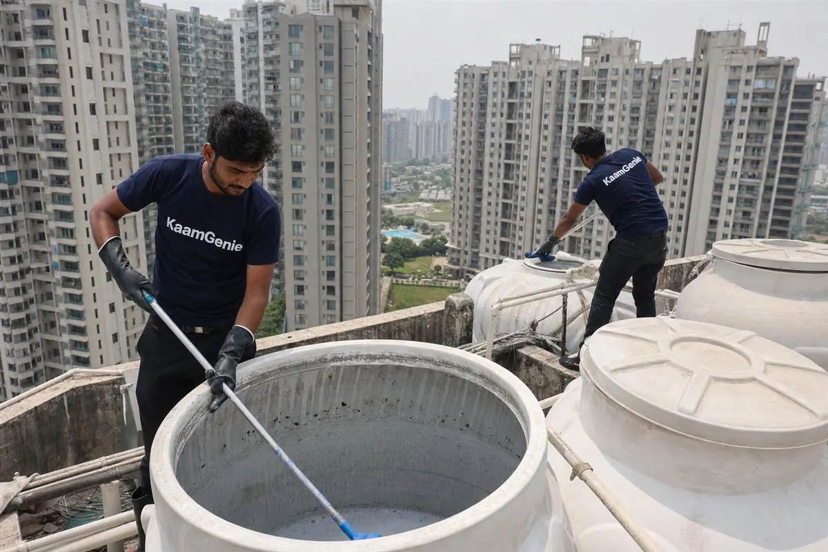 Calendar showing four quarterly water tank cleaning dates pinned to a Noida society notice board beside a tower
