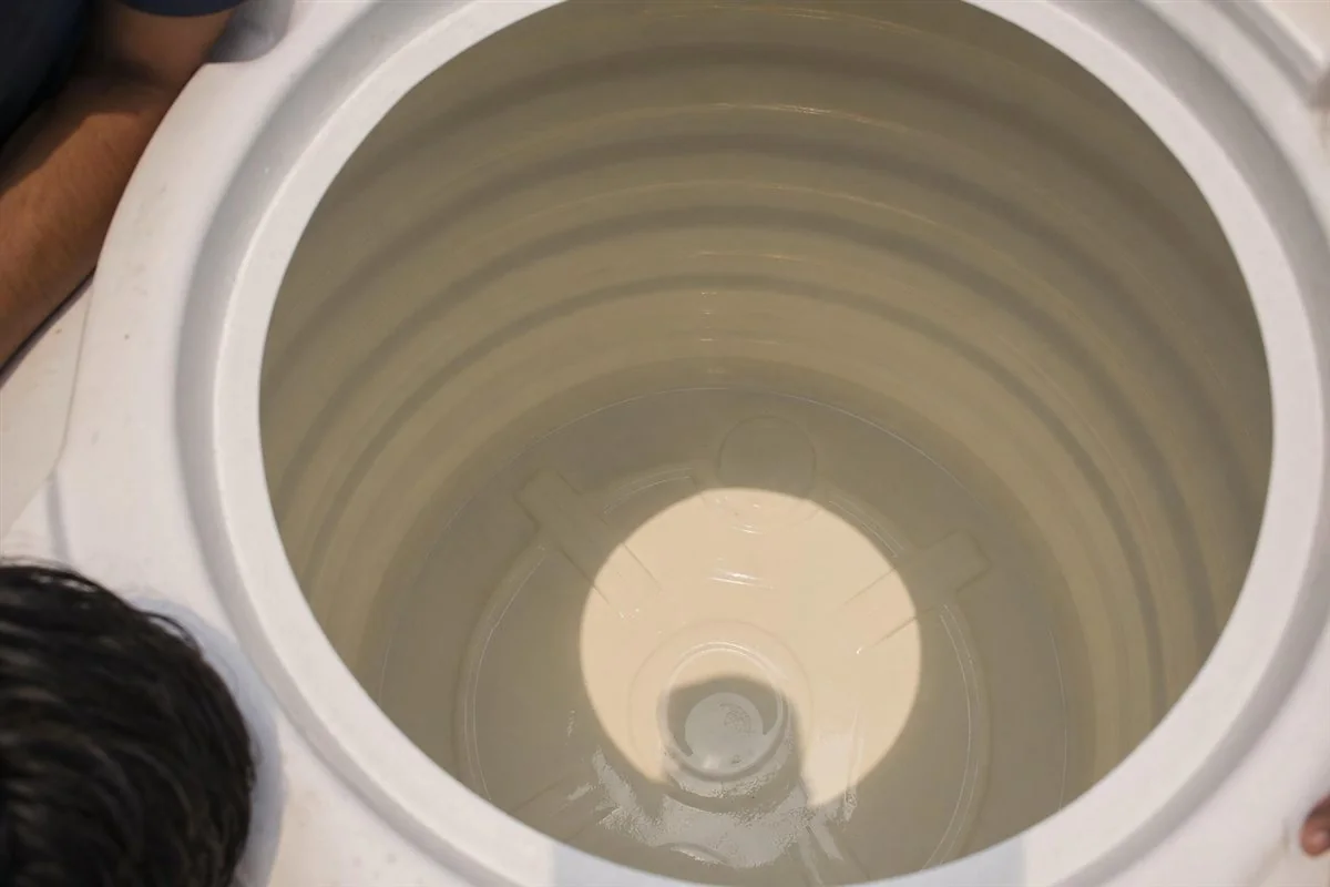Close-up of a sparkling clean plastic water tank interior in a Noida flat immediately after a KaamGenie cleaning, walls and floor free of sludge and scale