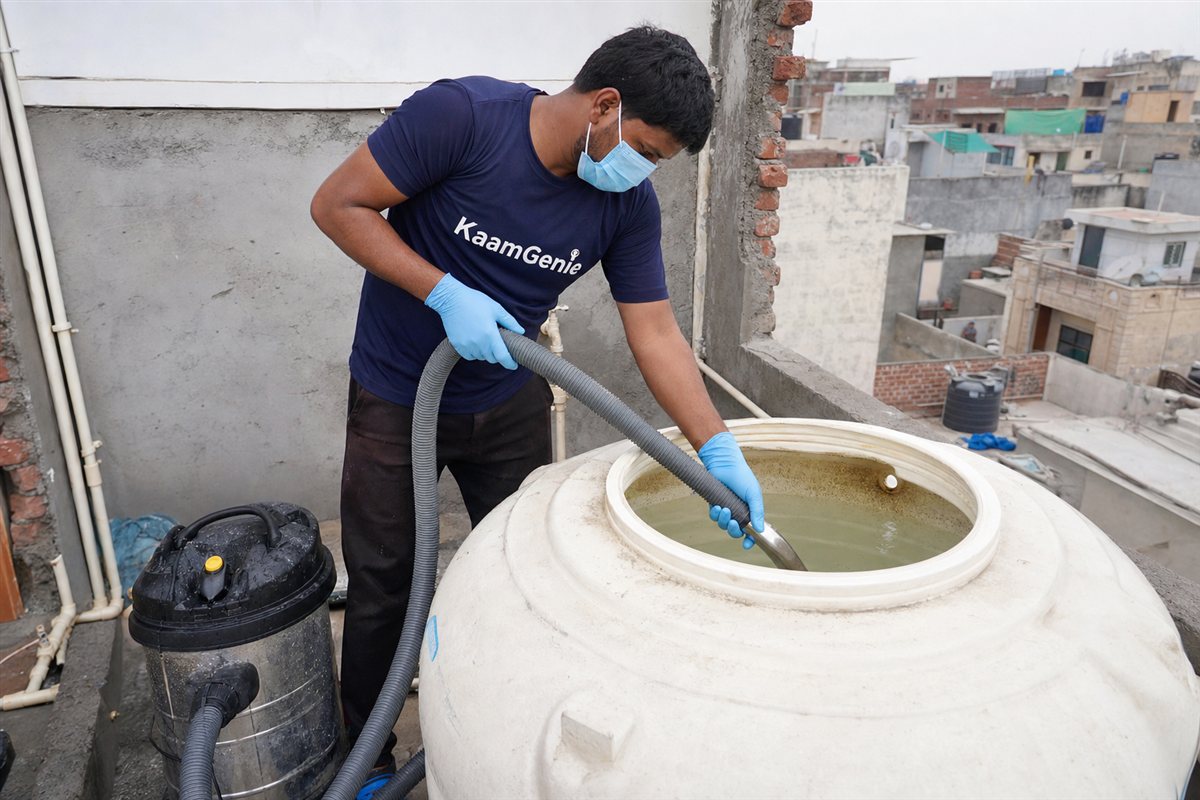 KaamGenie technician cleaning a rooftop overhead water tank of a 2BHK Delhi flat with vacuum equipment