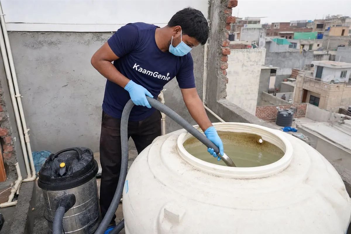 KaamGenie technician cleaning a rooftop overhead water tank of a 2BHK Delhi flat with vacuum equipment