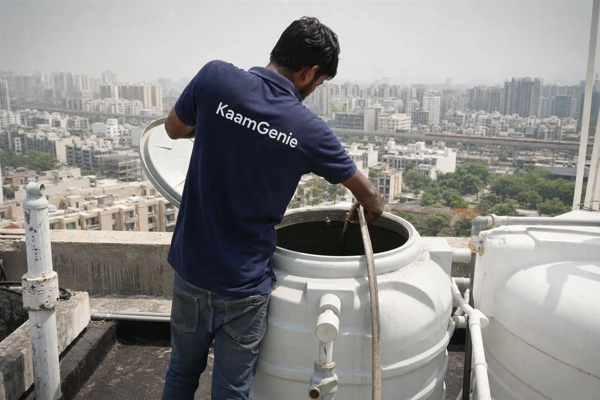 Diagram-style view of a New Gurgaon high-rise water system: tanker and borewell feeding a large underground reservoir, pumped up to multiple rooftop tower tanks