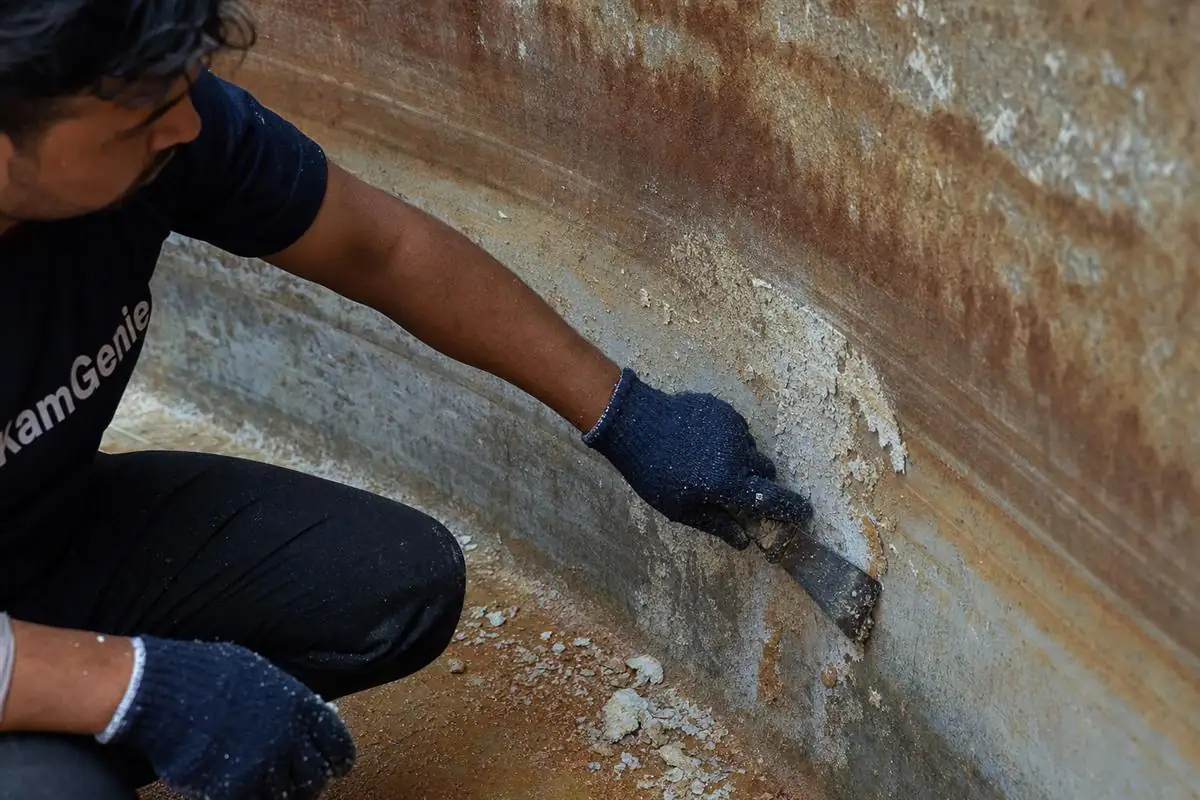 Close-up of heavy calcium and iron scale build-up on the wall of a Greater Noida West society underground reservoir before cleaning