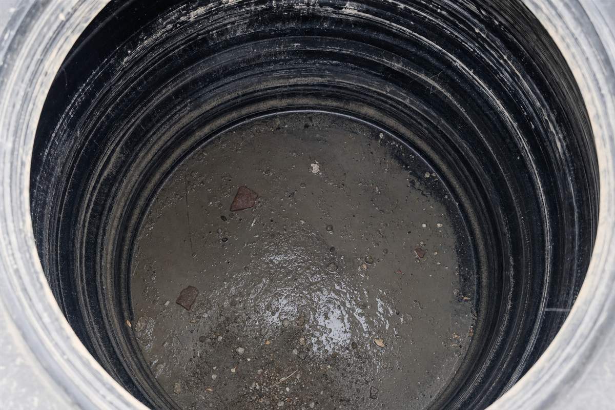 Grey cement slurry, sand and plastic pipe shavings settled at the bottom of a newly handed-over water tank in a Gurgaon flat