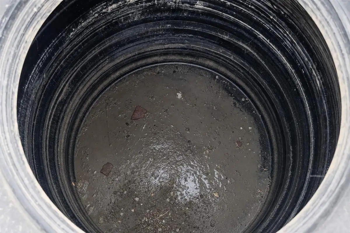 Grey cement slurry, sand and plastic pipe shavings settled at the bottom of a newly handed-over water tank in a Gurgaon flat