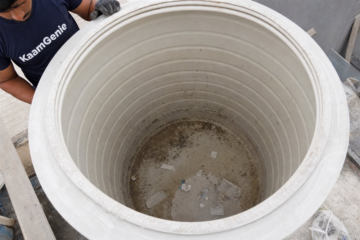 Construction debris on the floor of a new Noida tower water tank - set cement patches, grey sand, plaster flakes, plastic packing offcuts and metal filings