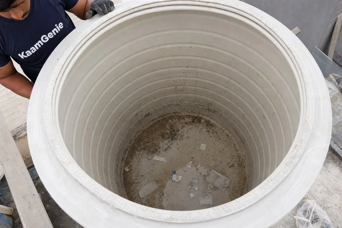 Construction debris on the floor of a new Noida tower water tank - set cement patches, grey sand, plaster flakes, plastic packing offcuts and metal filings