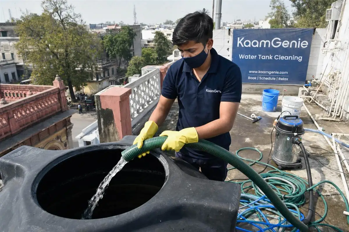KaamGenie technician in navy uniform draining an old rooftop water tank on a heritage house in Civil Lines North Delhi