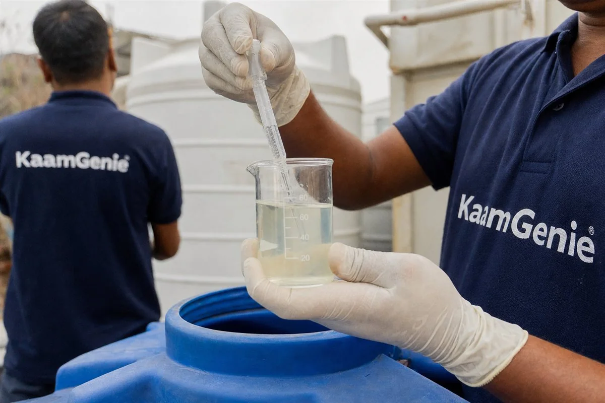 Close-up of gloved hands measuring food-grade chlorine solution into a beaker before disinfecting a water tank in Delhi
