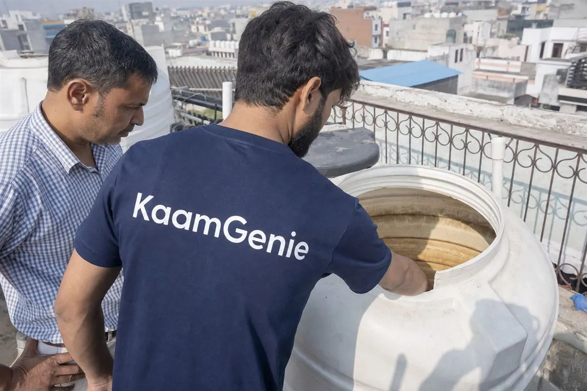KaamGenie crew member showing a Delhi resident the dirty interior of their rooftop water tank