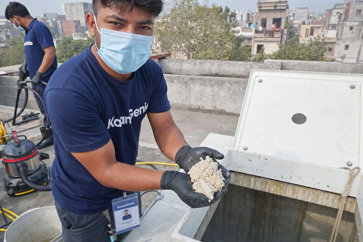 KaamGenie technician showing thick white chalky scale deposits scraped from inside a Delhi overhead water tank affected by hard water